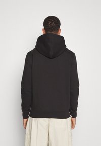 Felpa nera con una grande e morbida cappuccio, polsini e orlo a costine. Il tessuto sembra liscio e spesso, adatto per l'abbigliamento informale.