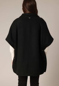 Zwart wollen blend poncho met een textuurafwerking, voorzien van een kraag, korte mouwen en knoopaccenten langs de zijkant.