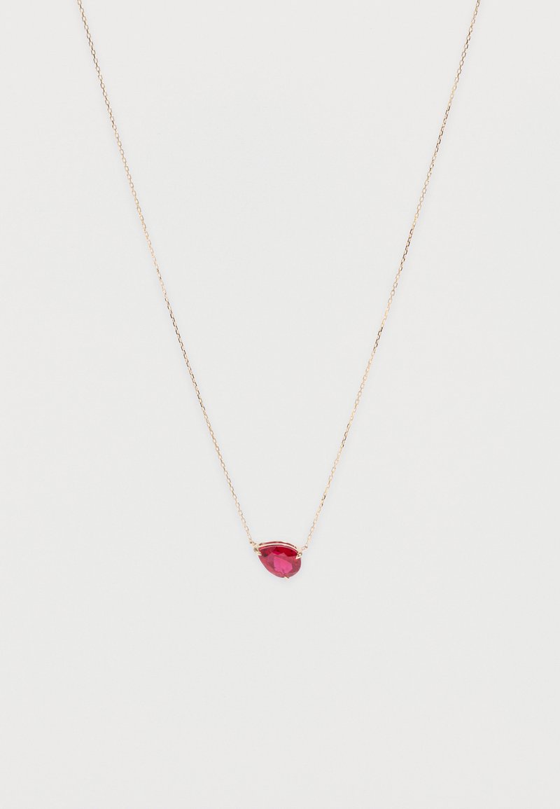 Collar delicado de cadena de oro con un pequeño colgante de piedra preciosa roja en forma de lágrima, centrado sobre un fondo blanco.