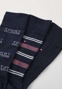 Calcetines de color navy con tres diseños: uno con el texto impreso "TOMMY HILFIGER", otro con rayas horizontales y uno más con un pequeño logo de acento.