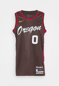 Maglia da basket marrone con accenti rossi, testo bianco "Oregon" e numero "0". Presenta una texture in rete e il logo Nike. Marchio NBA sull'orlo.