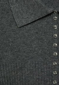 Grå ribbet striktrøje med krave og en lodret række af seks knapper på forsiden. Stoffet har en subtil tekstur og en let glans.