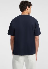T-shirt a maniche corte blu navy in cotone morbido, con colletto a girocollo e vestibilità rilassata, senza loghi o motivi visibili.