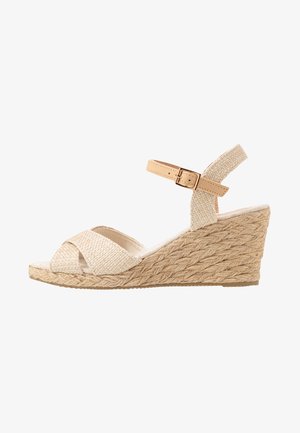 Béžové tkané espadrilové wedge sandály s texturovaným textilním svrškem, zkříženými popruhy a kotníkovým páskem zajištěným zlatým sponou.