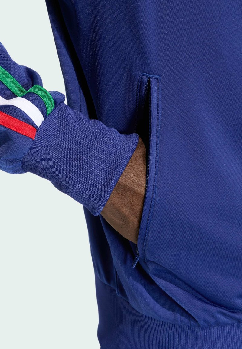 Marineblauwe sweatshirt met ritszak. Kenmerkt zich door ribgebreide manchetten met groene, witte en rode strepen. Zachte textuur, aansluitend design en slanke silhouet.