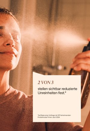 Brown mist spray bottle releasing a fine mist, a person is applying it to their face, with soft lighting and close-up focus on skin texture.