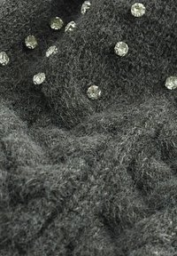 Hallidega villane kootud kangas, millel on udune tekstuur, ja sellega on laiali asetatud selged rhinestone'id, mis toovad pehmele pinnale lisadetaili ja visuaalset huvi.