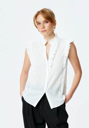 Witte mouwloze blouse met een gerimpelde kraag en knoopsluiting. Gemaakt van lichte stof, met een gladde, vloeiende textuur.