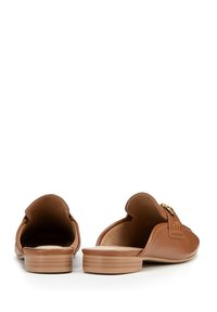 Scarpe slip-on in pelle marrone con una texture liscia, apertura arrotondata sul retro e dettagli decorativi in metallo color oro sulla parte anteriore. Suola di colore chiaro.