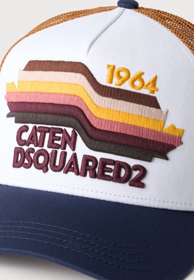 Casquette blanche et marine avec dos en maille marron, présentant des bandes brodées colorées, "1964" en jaune, et "CATEN DSQUARED2" en marron foncé.