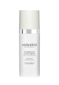 Hvit sylinderformet beholder med strukturelt blomsterdesign, sølvbånd og lys grønn kork. Merket sier "Nærende Nattkrem" for sensitiv hud.