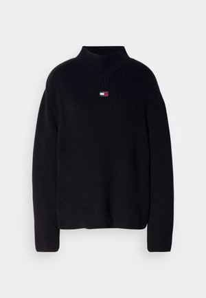 Black knitted sweater with a high, ribbed mock neck and a small, rectangular logo featuring red, white, and blue accents on the chest.
