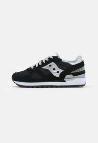 Zwarte sportieve schoen met een bovenwerk van suede en mesh, zilveren accenten, dikke witte tussenzool, ronde veters en een patroon op de rubberen zool.
