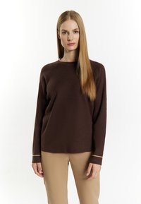 Brauner Strickpullover mit langen Ärmeln, runder Ausschnitt und kontrastierenden beigen Akzenten an den Bündchen. Weicher Stoff, lässige Passform.