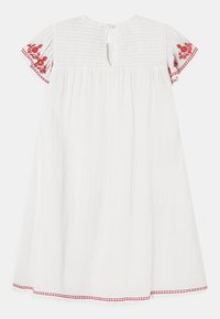 Bílé šaty s krátkými, vyšívanými rukávy s červenými květinovými vzory. Texturovaná tkanina s knoflíkovým zapínáním na zádech.