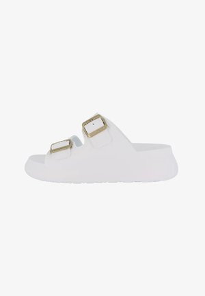 Sandalo slip-on bianco con due fibbie dorate regolabili e suola piatta texturizzata, visto di lato.