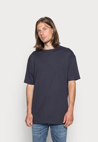 Tricou scurt cu maneci, de culoare bleumarin închis, cu o croială lejeră, fabricat din bumbac moale. Are un decolteu tip crew și un design simplu, fără modele sau accente.