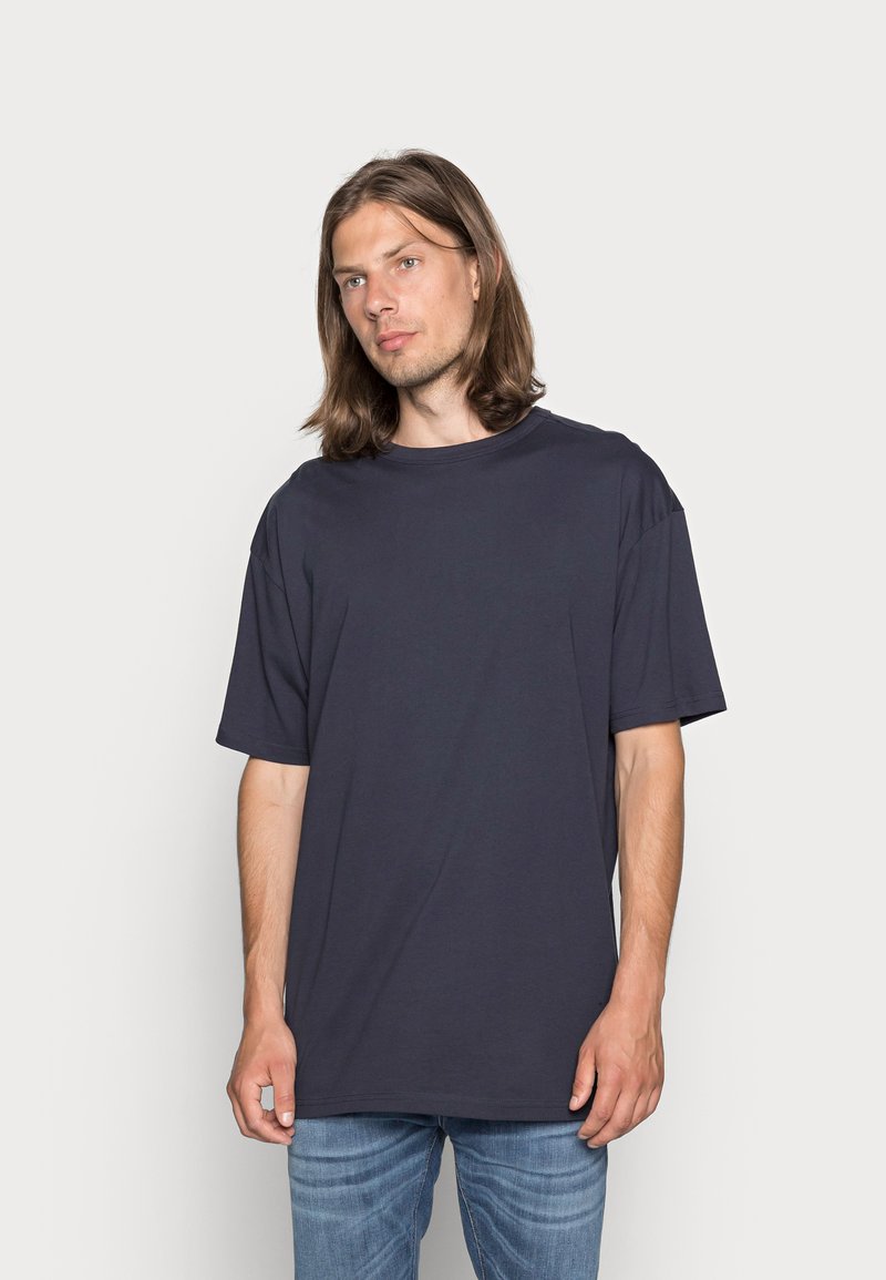 T-shirt a maniche corte blu navy scuro in un taglio rilassato, realizzato in cotone morbido. Presenta un colletto tondo e un design semplice senza fantasie o dettagli.