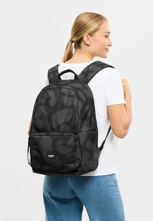 Sac à dos noir avec un motif texturé, présentant des sangles ajustables, une poignée supérieure et une poche zippée à l'avant. Le matériau semble durable.
