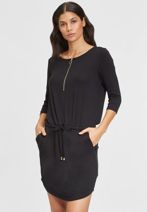 Robe noire à manches trois-quarts, col rond, détail de fermeture éclair, taille avec cordon de serrage et poches latérales ; tissu doux avec une texture lisse.