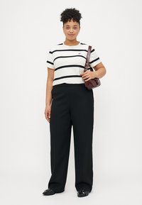 Fehér és fekete csíkos, rövid ujjú felső, fekete, bő szárú nadrág és fekete lapos cipő. Bordó kézitáska vállpánttal.