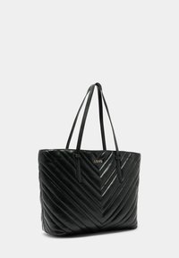 Zwarte gewatteerde draagtas met visgraatpatroon, gemaakt van synthetisch materiaal, voorzien van twee lange handvatten en een gouden logo-accent.