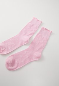Calzini di cotone rosa con pois bianchi, caratterizzati da un bordo ondulato in cima e una texture liscia.