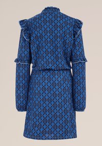 Blå mönstrad klänning med lång ärm, volangdetaljer vid axlarna och en figurnära midja. Materialet verkar vara texturerat med en intrikat diamantdesign.