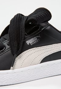 Černé kožené tenisky s texturovanou černou tkaničkou, šedými semišovými akcenty a bílou gumovou podrážkou. Obsahují logo "PUMA BASKET" v stříbrné barvě.