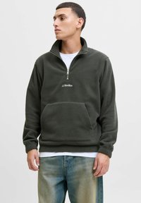 Dark green fleece pullover with half zip, featuring a front pouch pocket and white "JJ Studios" logo, textured surface, and ribbed cuffs.