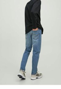 Jeans i ljusblå denim med avslappnad passform, med bakfickor och lätt urtvättning. Kombinerade med sneakers i neutrala toner och en svart tröja.