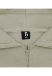 Beige zip-up hoodie with a soft interior lining. Centered label shows "B large." Metal zipper and stitching details are visible.