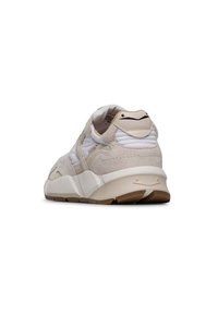 Sneaker beige e bianco con materiali in suede e mesh, linguetta imbottita, suola spessa e dettagli testurizzati sul tallone.