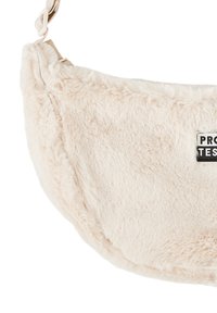 Nepbont tas in zacht beige, met een ronde vorm, ritsluiting en een zwart label met de tekst "PRO TEST" voor extra detail.