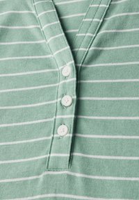 Chemise henley rayée verte avec des rayures horizontales blanches, un plastron à trois boutons et une texture en coton douce.