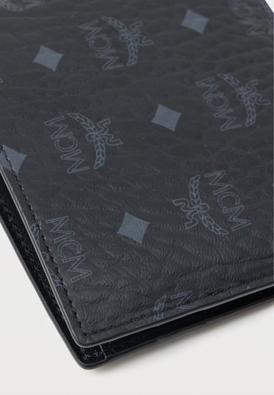 Μαύρο δερμάτινο πορτοφόλι με πλεκτή υφή, που διαθέτει ανάγλυφο λογότυπο MCM και σχέδια διαμαντιών. Απλός σχεδιασμός με καθαρές άκρες.