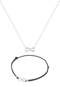 Silberne Unendlichkeitssymbol-Halskette an einer zarten Kette, kombiniert mit einem braunen Lederarmband, das einen passenden Unendlichkeitsscharm hat.