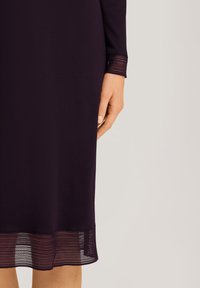 Abito viola con maniche lunghe e un accento in pizzo all'orlo. Il tessuto è liscio con una silhouette leggermente aderente.