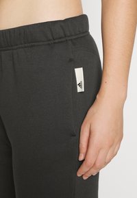 Grå bomullsblandning sweatpants med elastisk midja, med sidofickor och en vit tygetikett nära fickan.