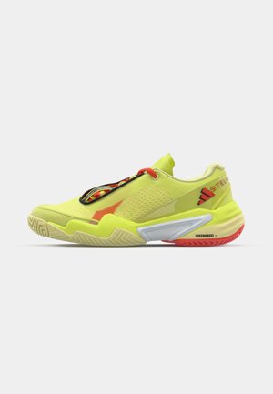 Neonsko rumene atletske čevlje z teksturiranim zgornjim delom, elastičnimi vezalkami, rdečimi detajli in večbarvno peto. Imajo belo srednjo podplato in vzorčen podplat.