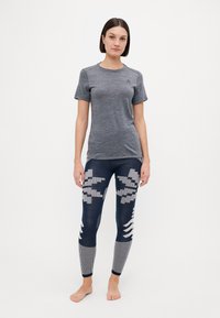 T-shirt de sport gris à manches courtes, associé à un legging marine avec un motif géométrique et des accents texturés sur le bas des jambes.
