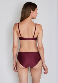 Ensemble bikini bordeaux avec texture côtelée. Bretelles ajustables, fermeture par crochet à l'arrière, et bas taille haute.