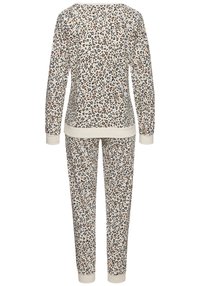 Sada loungewear s leopardím vzorem v krémové barvě, která se skládá z dlouhého rukávu a odpovídajících kalhot. Vyrobeno z měkké tkaniny s žebrovanými manžetami a lemem.
