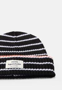Beanie lavorato a maglia a righe bianche e nere con un accento arancione, dotato di un'etichetta con il marchio sul risvolto. Texture morbida e a coste.