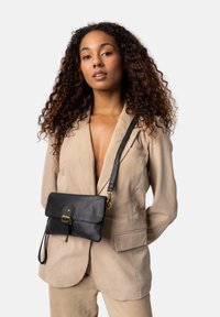 Borsa a tracolla nera in pelle con chiusura a patta e hardware dorato, dotata di tracolla removibile e superficie liscia.