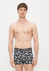 Melni bokseršorti ar vidukļa joslu, kurā redzams uzraksts "KARL LAGERFELD." Audumam ir atkārtots raksts ar brillēm un siluetiem.