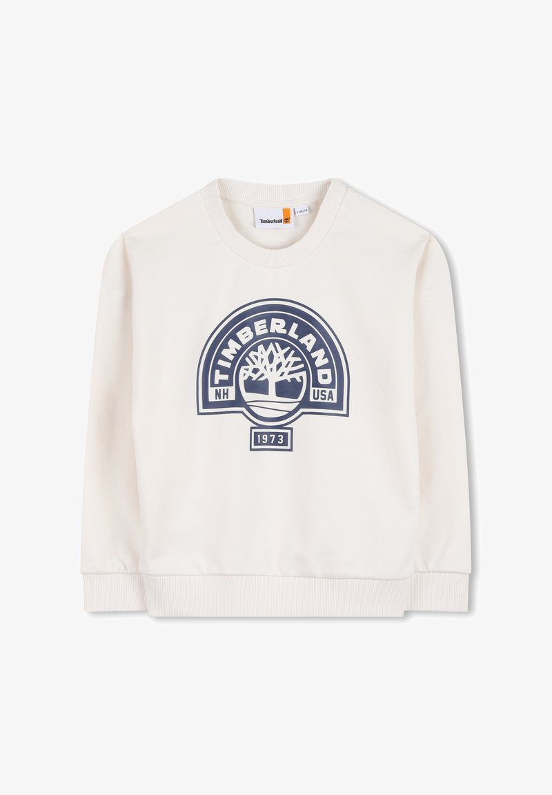 Sweat-shirt couleur crème, arborant un logo Timberland bleu avec un dessin d'arbre. Col rond et poignets côtelés ; tissu doux et texturé.