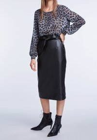Leopardenmuster durchsichtige Langarmbluse mit schwarzem Leder-Bleistiftrock und schnürbaren schwarzen Absatz-Stiefeletten. Glatte Textur, taillierte Silhouette.