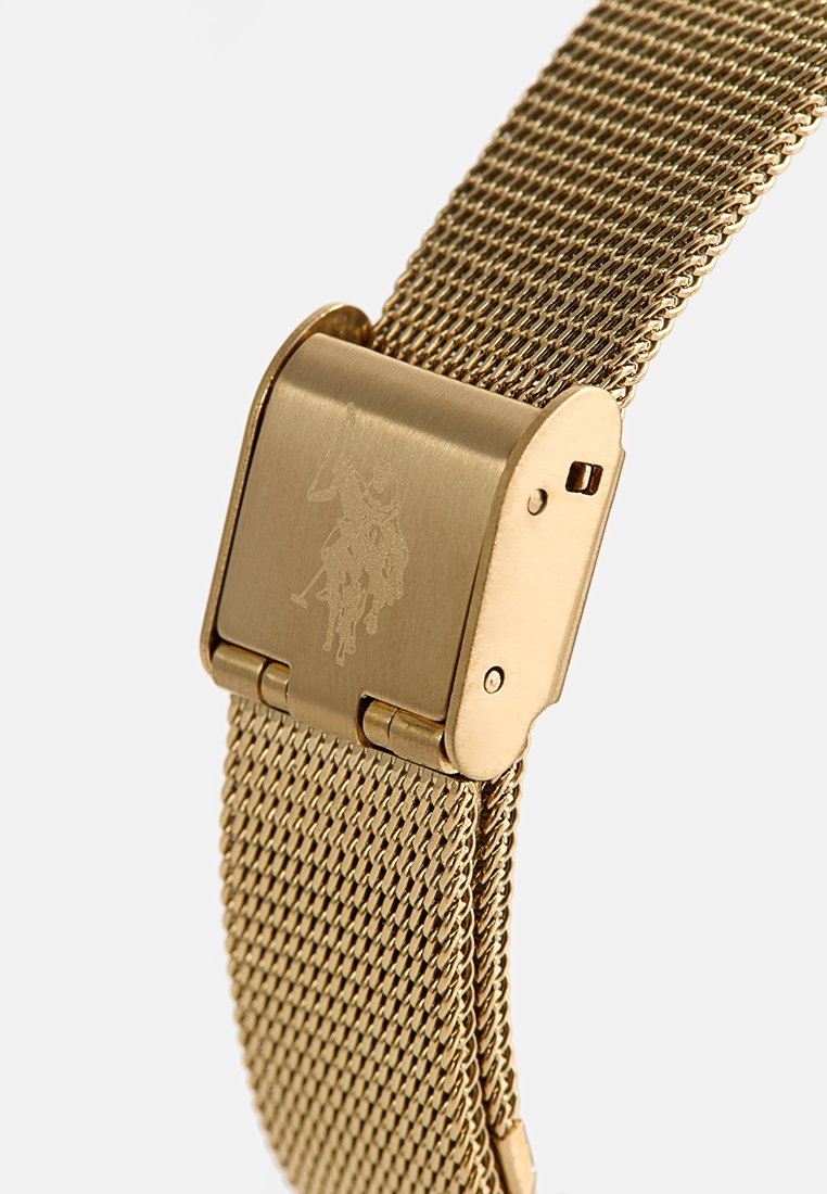 Bracelet de montre en métal maillé doré avec fermoir à rabat, arborant un logo de joueur de polo gravé.