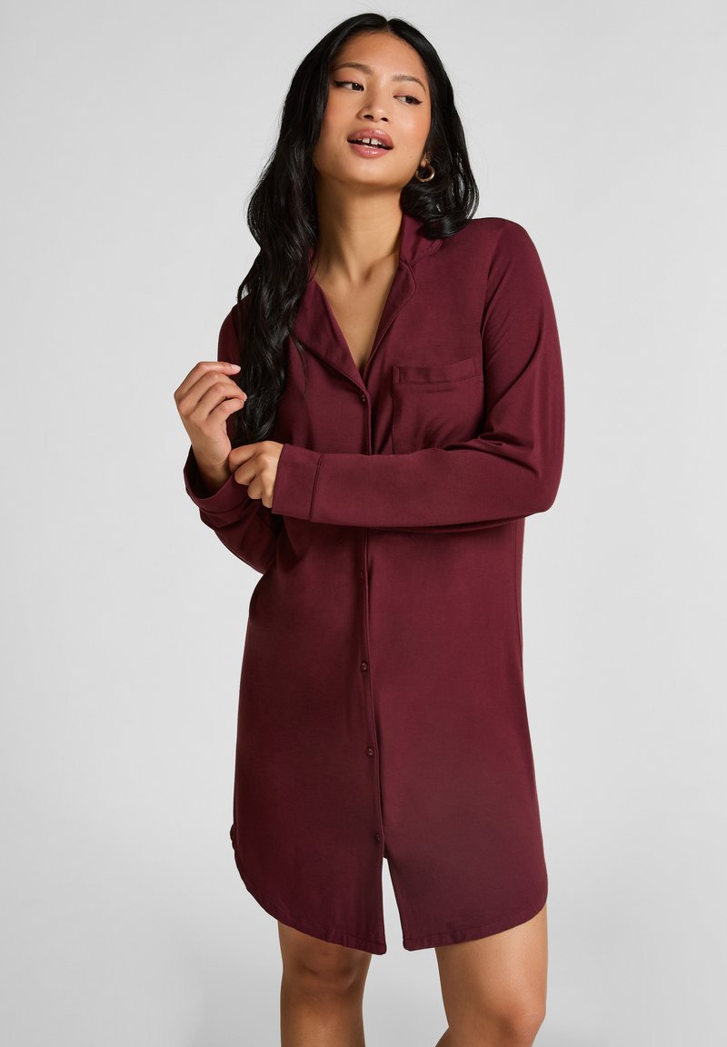 Bordeauxrotes Hemdkleid mit langen Ärmeln, einer einzigen Brusttasche, glatter Textur und einem lockeren Schnitt, der oberhalb des Knies endet.